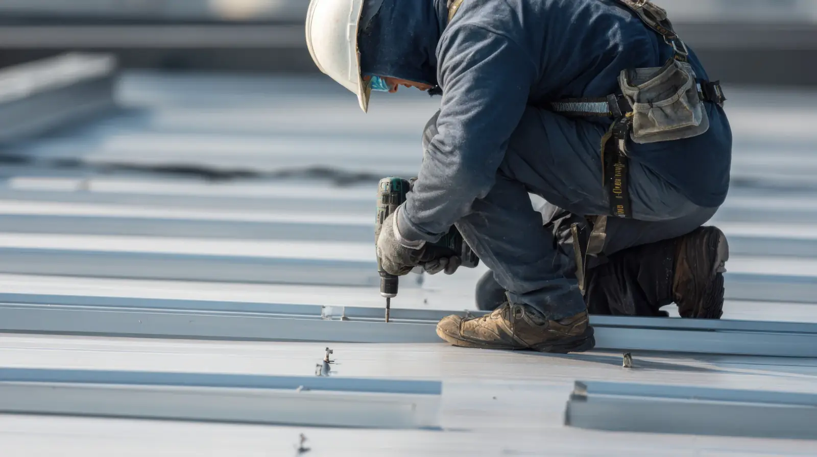 Roofer fastening panels on a low-slope commercial metal roof